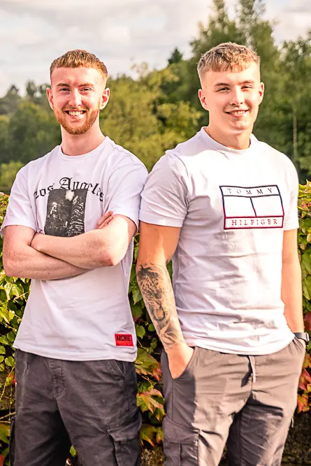 Family portrait of 2 young adult brothers outdoors.