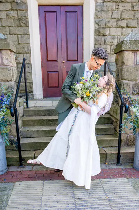 Bride and groom outside Peel Street Baptist Church, Accrington, with groom dipping the bride