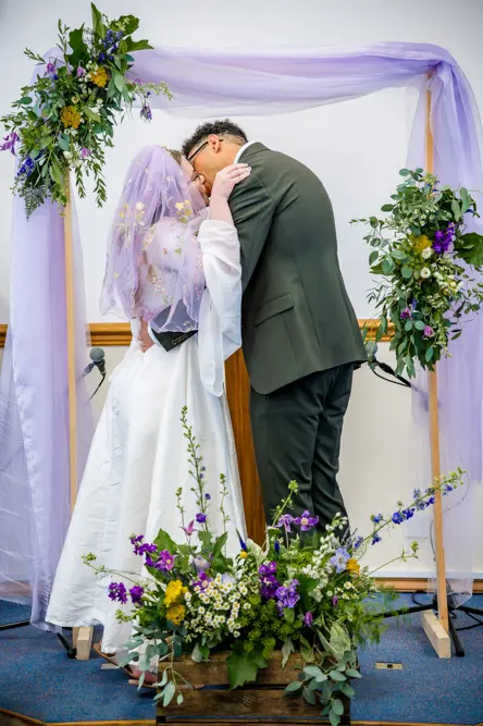 Bride and groom sharing their first kiss during their wedding ceremony at Peel Street Baptist Church, Accrington