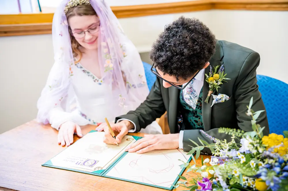 Bride and Groom signing the register (not the official one)