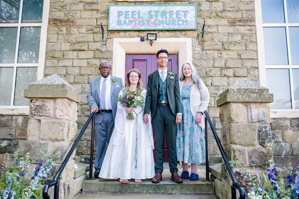 Bride and groom with the groom's parents outside Peel Street Baptist Church, Accrington