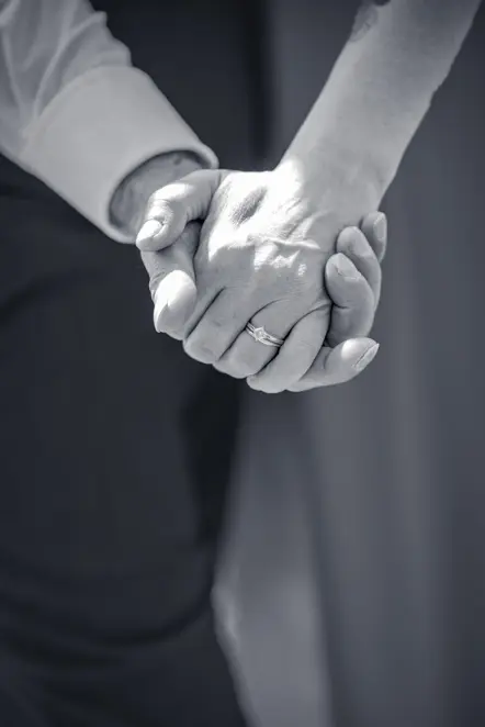 Black-and-white image of Close-up of couple holding hands showing off the ladies engagement ring