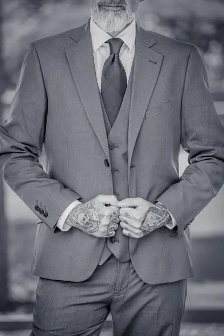Black-and-white image of Close-up of Man holding the front of his suit jacket taken by Manchester Photographer Wedding Rebekah Morecroft