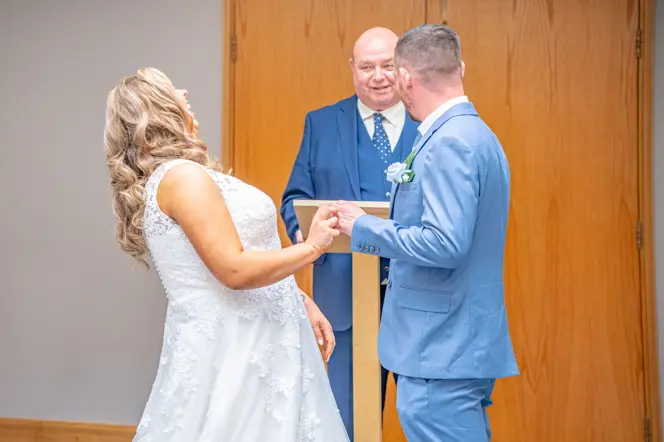 Bride putting ring on the groom's finger while laughing