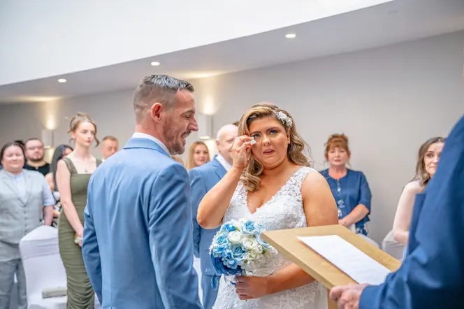 Couple saying their vows during as the bride wiping away a tear