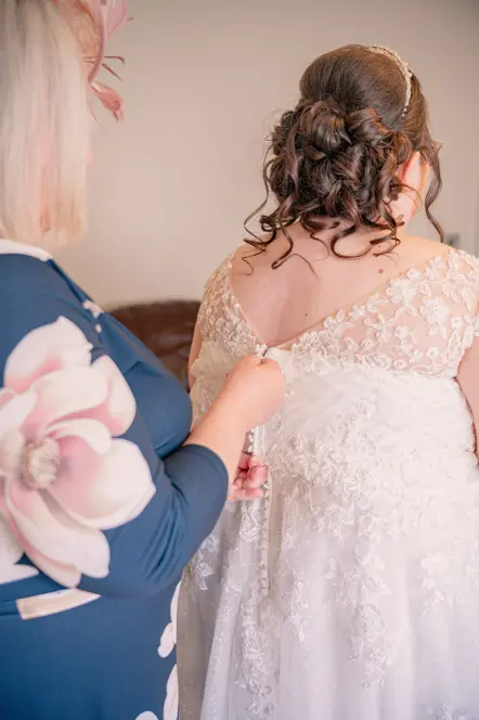 Mother of the bride fastening the bride dress