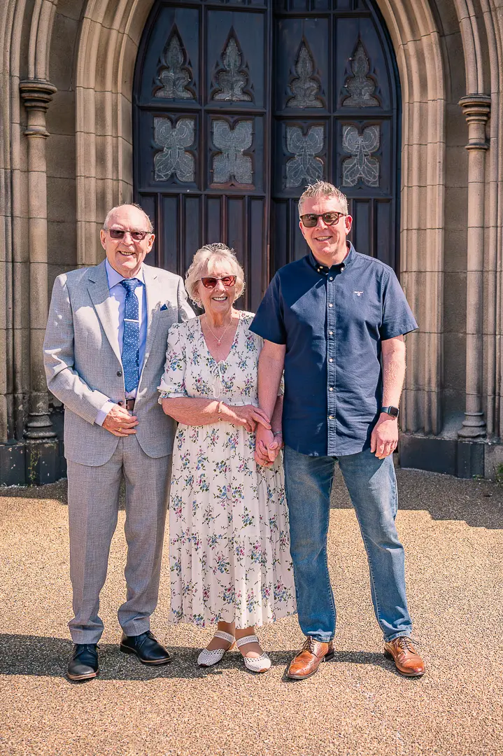 Older couple with their son outside St Peter’s Church, Ashton-under-Lyne, after traditional Christian wedding vow renewal