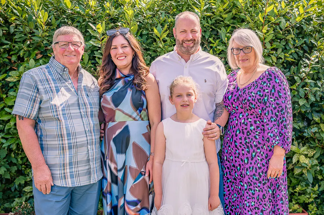 Parents posing with their son, daughter-in-law and granddaughter at the reception.