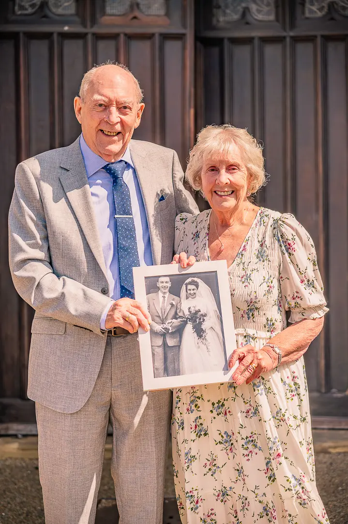 Dennis and Patricia holding their original wedding photograph 70 years later