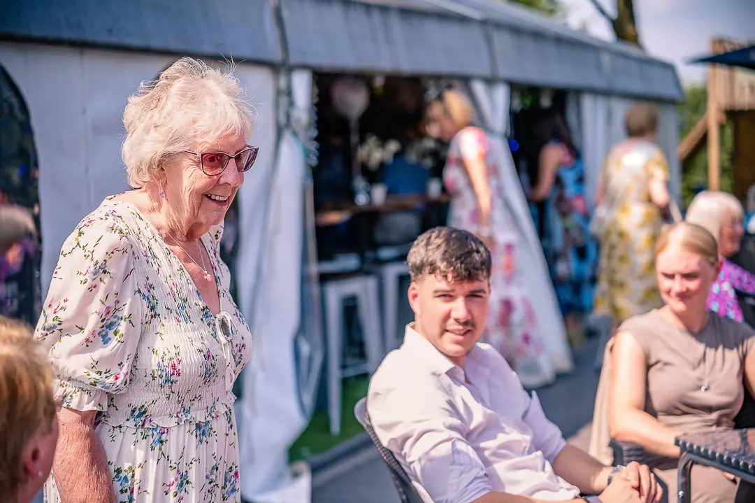 Wedding guests chatting together outside in the sunshine during the reception.