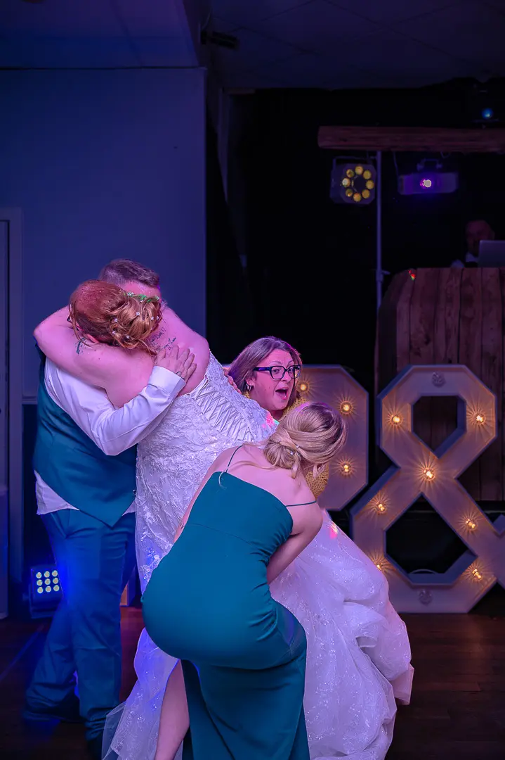 Two women lifting the bride off the ground as the groom holds her, capturing the playful, celebratory atmosphere of a classic wedding at Bucks Bar