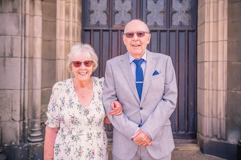 couple-outside-st-peters-ashton Dennis and Patricia smiling outside St Peter’s Church during their 70th wedding vow renewal