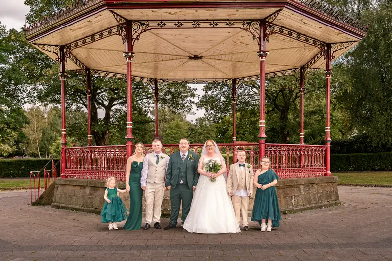 Wedding Party Bandstand Group Bride and groom with their wedding party, two young best men, two young bridesmaids and an adult bridesmaid, in front of the bandstand at Broadfield Park in Rochdale
