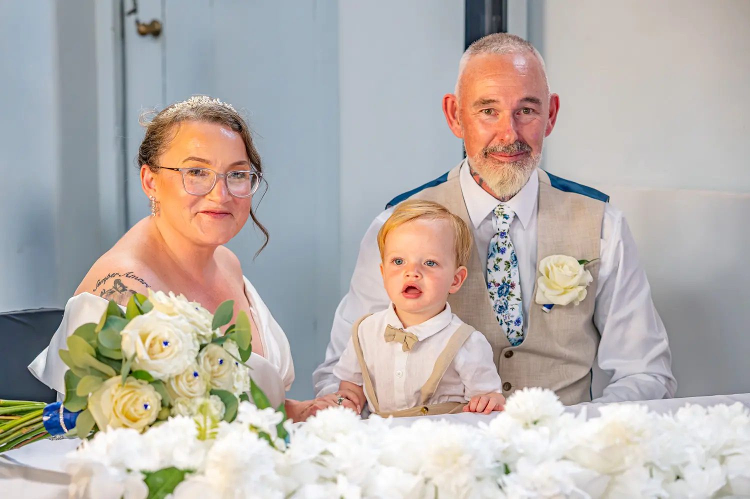 The bride and groom sitting together with their grandson during the ceremony