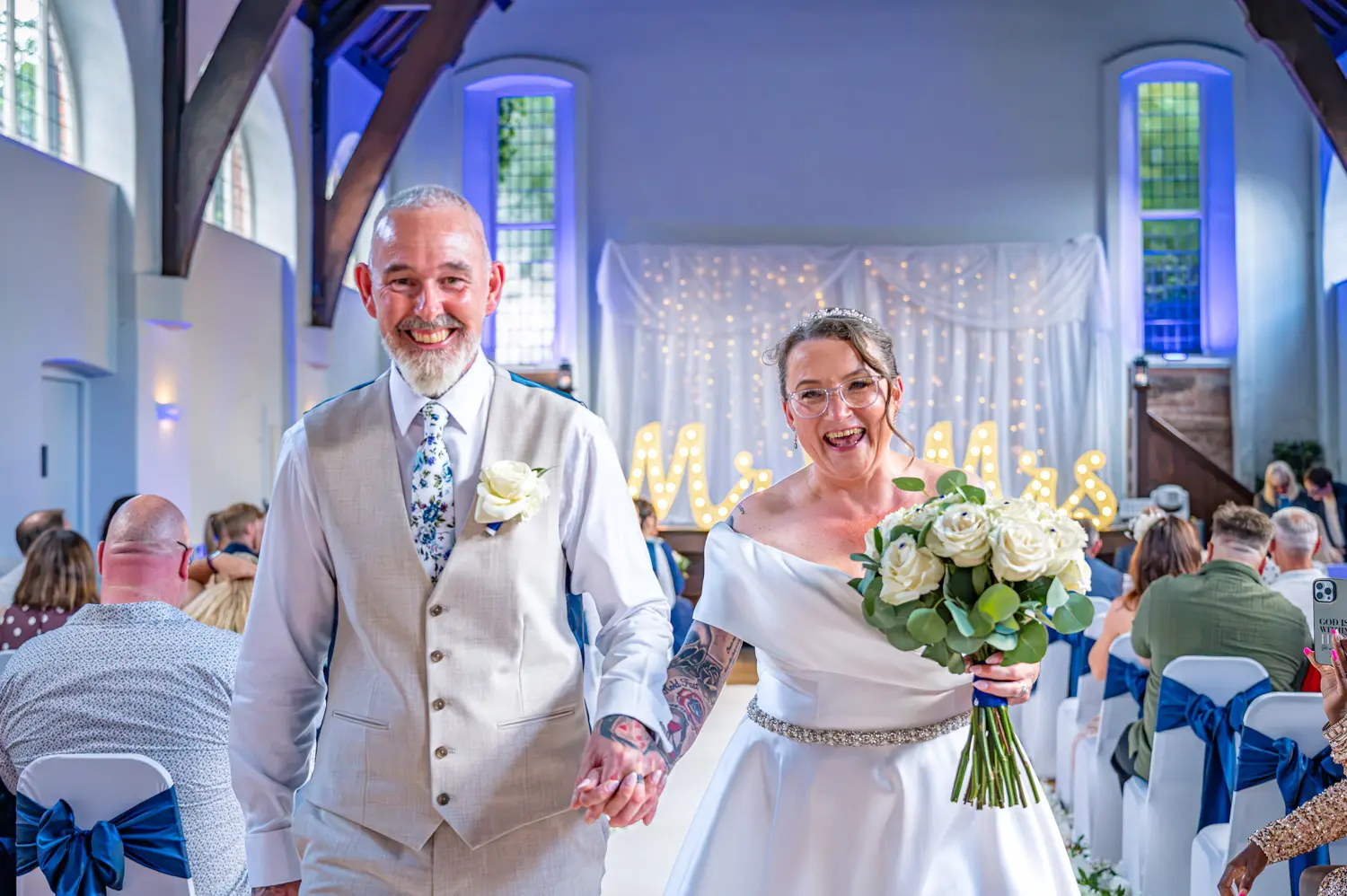 Close photograph of the couple walking back down the aisle smiling