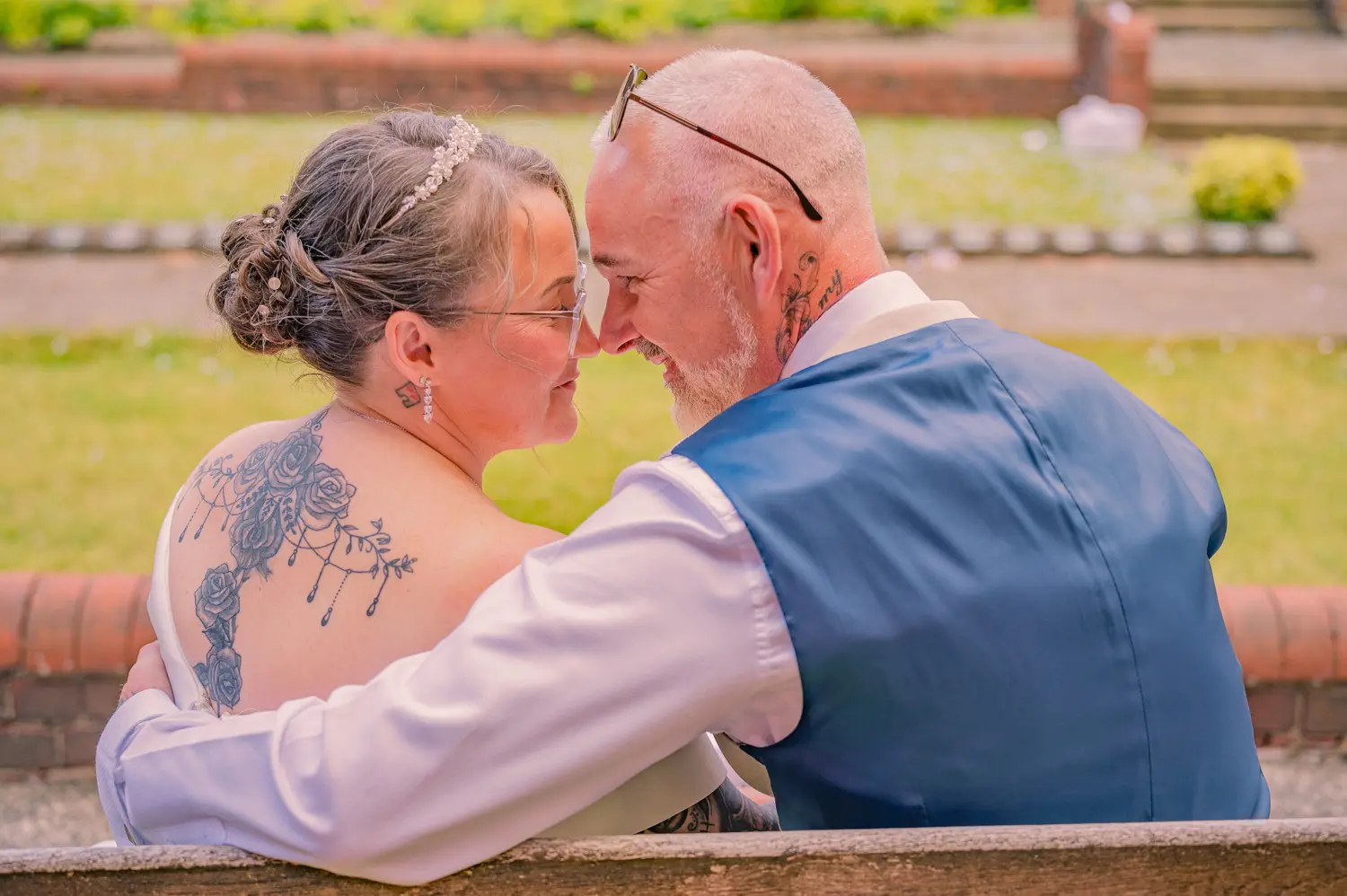 A creative shot taken from behind the bench as the couple lean in to touch noses