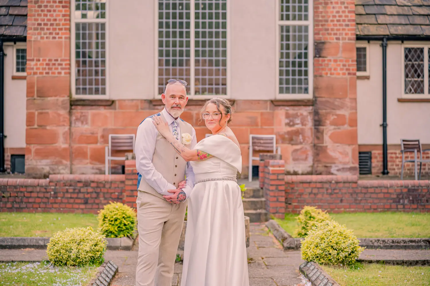 Wide portrait of the bride and groom, showing the full scale of the historic building