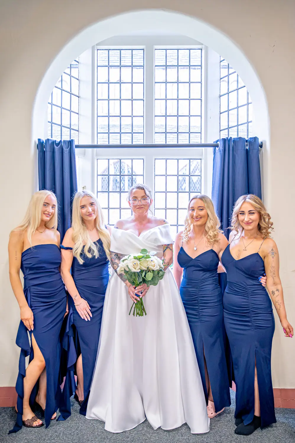 Four bridesmaids in matching robes laughing together in the dressing room