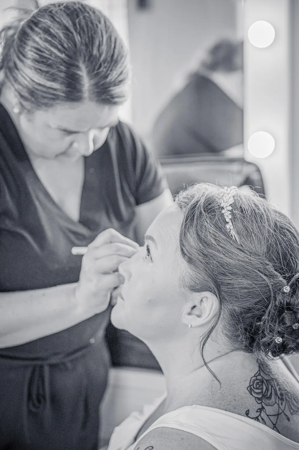 A bride having her makeup artist applies the finishing touches