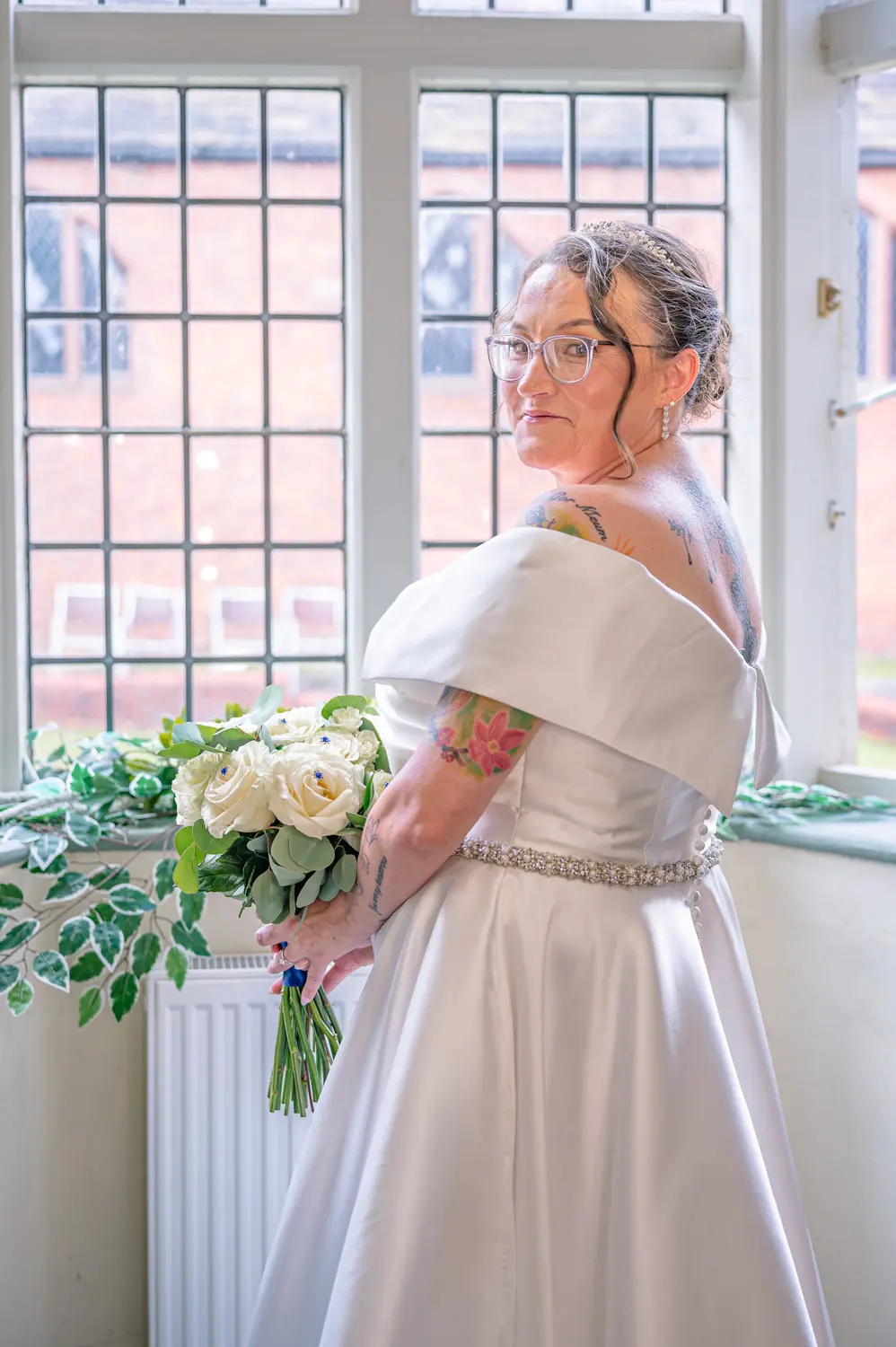 Portrait of the bride in her gown, softly lit by a large window