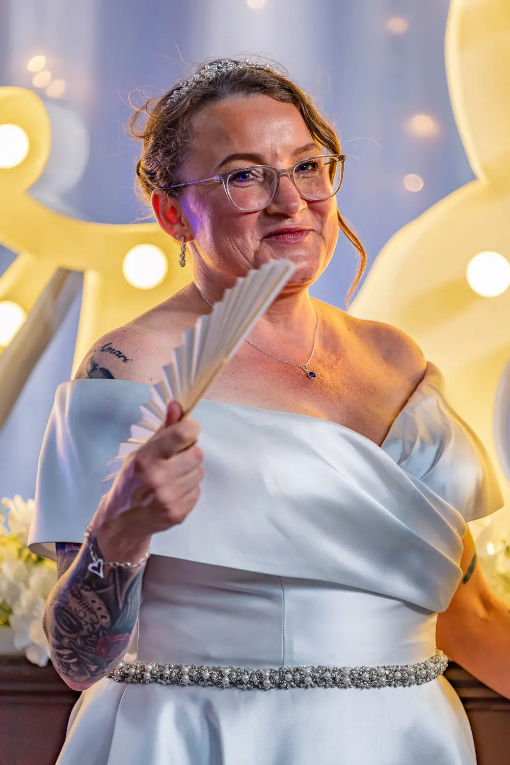 The bride listening to the groom's speech while holding a cooling hand fan
