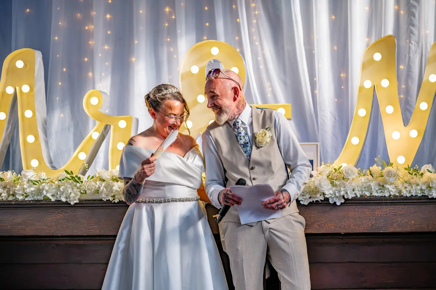 The bride and groom laughing together during a funny moment in the groom's speech