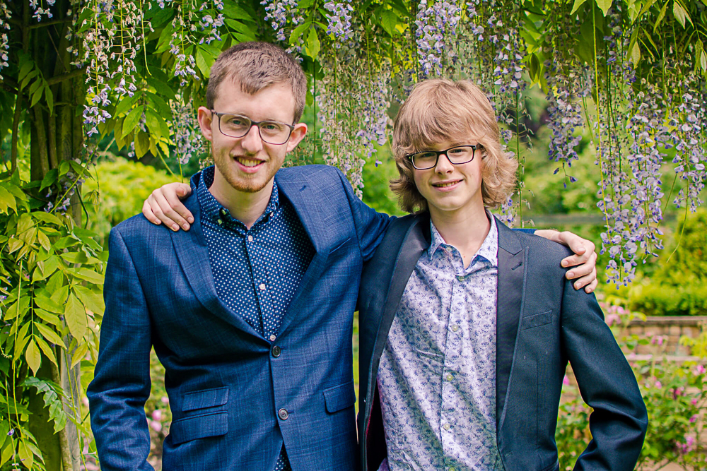Family portrait of 2 young adult brothers outdoors.