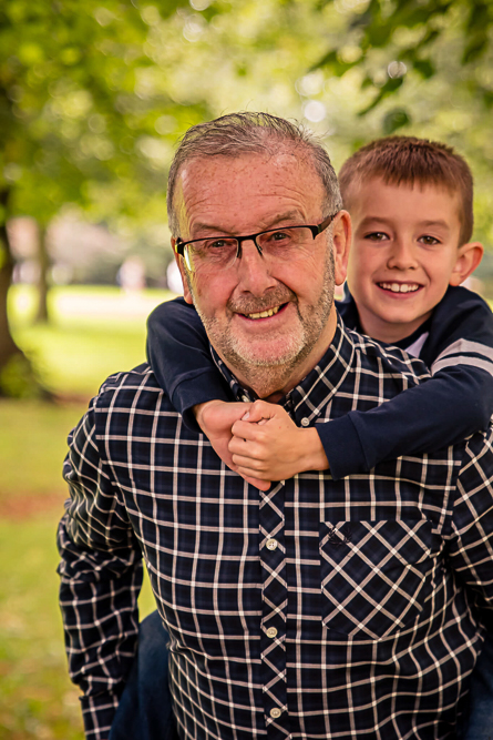 Outdoor Family Portrait of young boy piggybacked on granddad’s back