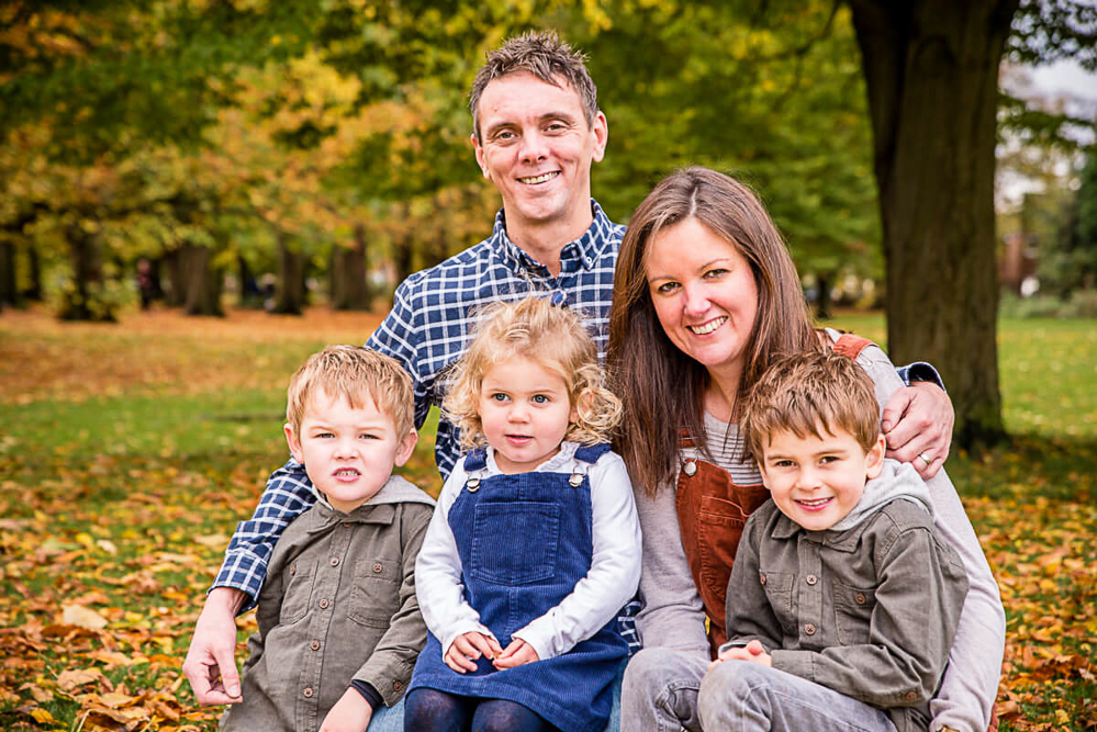 Outdoor Family Portrait of young family of 5 with autumn leaves and trees behind them