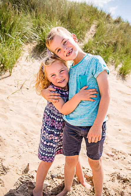 Outdoor Family Portrait of young bother and sister hugging on the beach