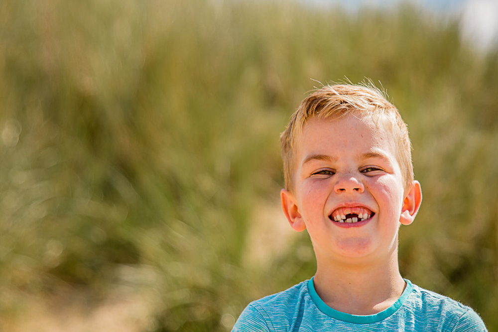 Outdoor Family Portrait of young boy on the beach smiling