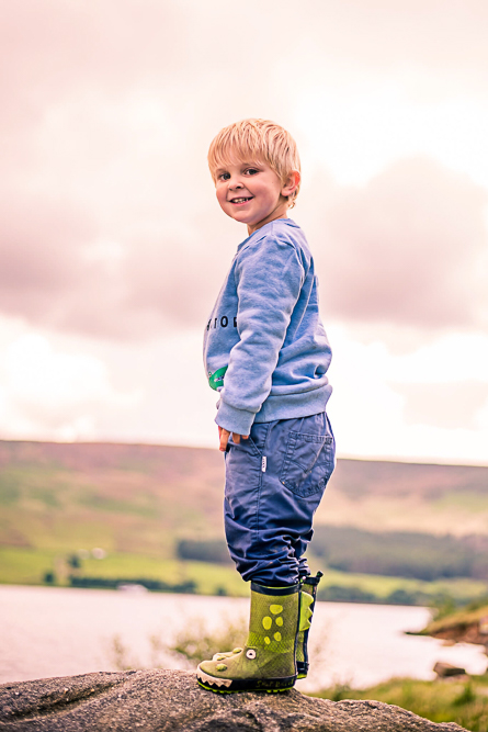 Outdoor Family Portrait of young boy standing on a rock