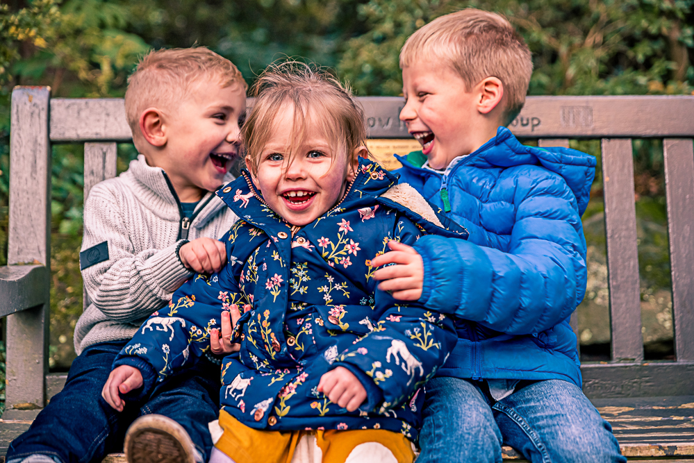 Outdoor Family Portrait of 3 young children laughing.