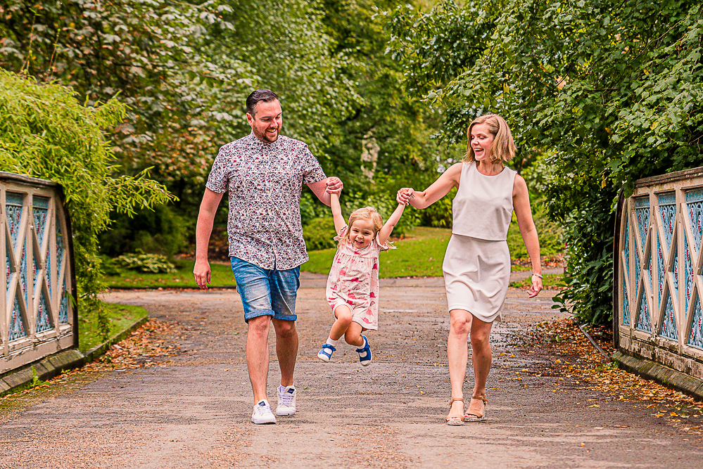Outdoor Family Portrait of family of 3 swing young daughter in the air