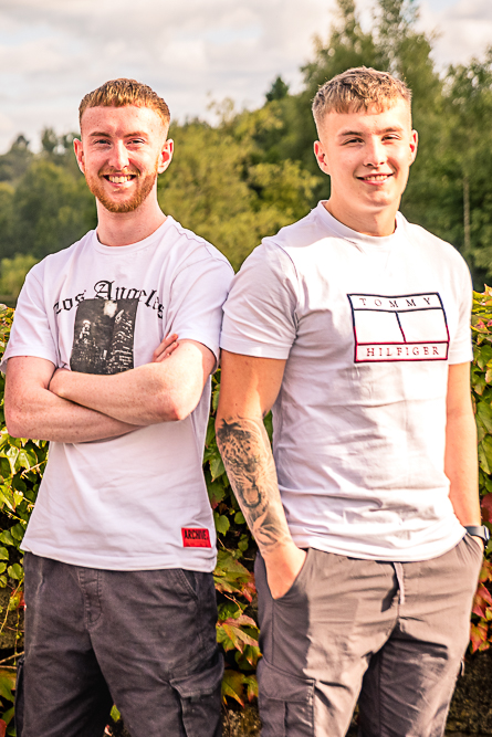 Family portrait of 2 young adult brothers outdoors.