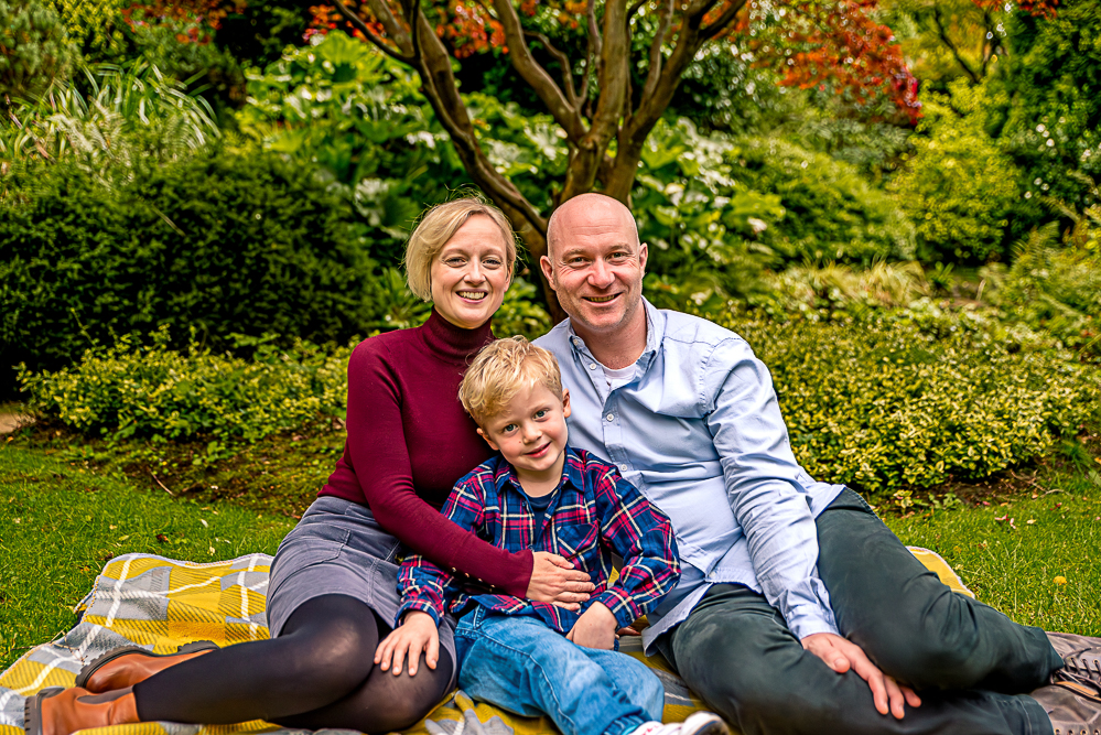 Outdoor Family Portrait of family of 3 seating on a blanket