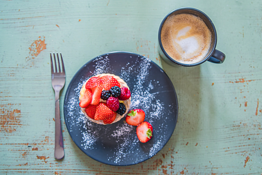 Fruit tart ona plate and cup of coffee