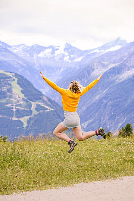 Outdoor Personal Brand Portrait of young woman jumping in the air with mountains in front of them
