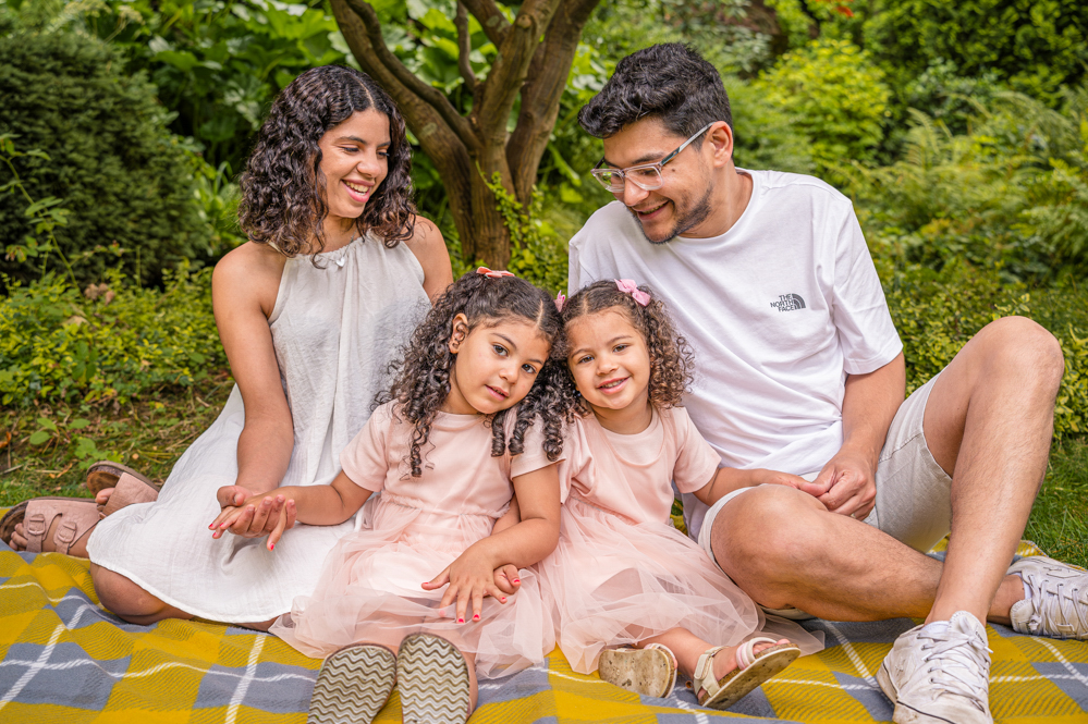 Outdoor Family Portrait of young family of 4 sitting on a blanket.