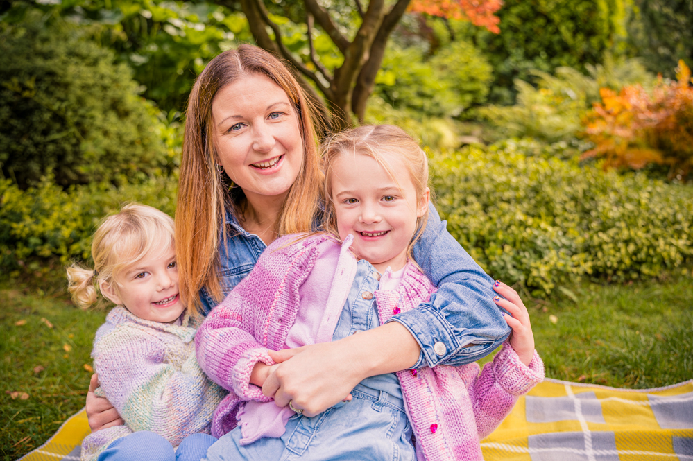 Outdoor Family Portrait of mother and 2 young daughters cuddling