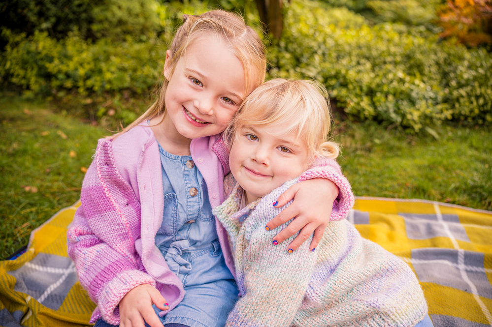 Two sisters cuddling outdoors, natural portrait photography
