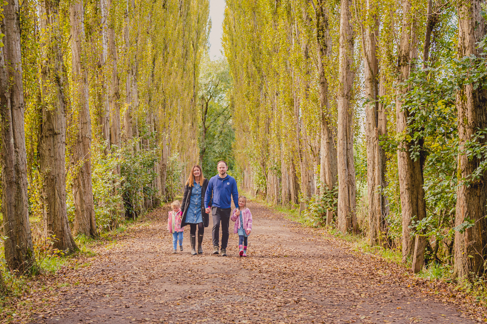 Outdoor Family Portrait of family of 4 walking with large trees around the edges