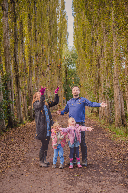 Outdoor Family Portrait of family of 4 throwing leaves in the air