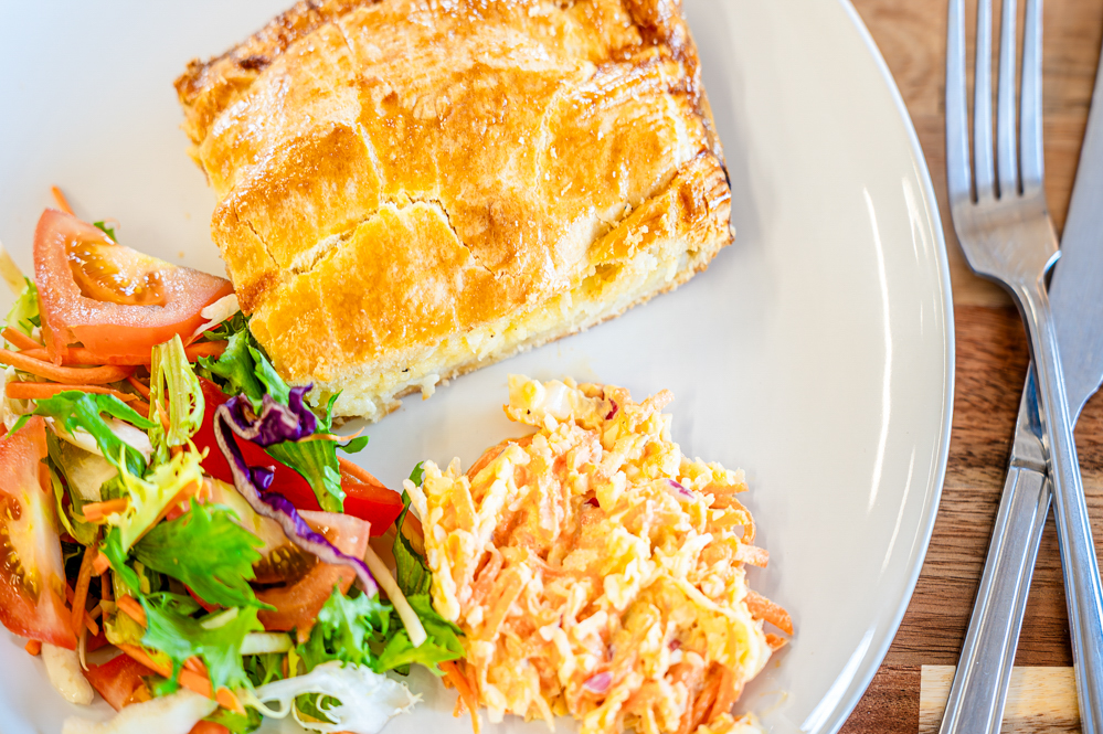 Cheese and onion pie, salad and coleslaw on a plate