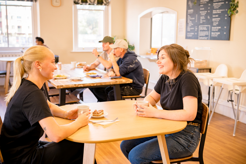 Two woman chatting over hot drinks and cake