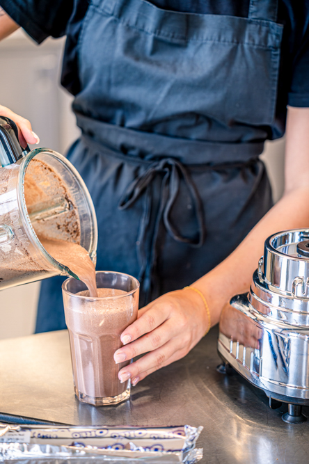 Person pouring chocolate Milkshake in glass