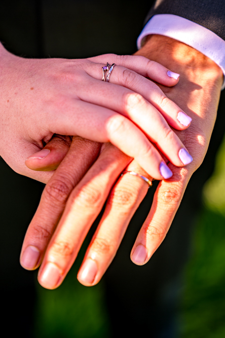 Bride and groom with hands on top of each other showing their wedding rings at Cronkshaw Fold Farm, Rossendale