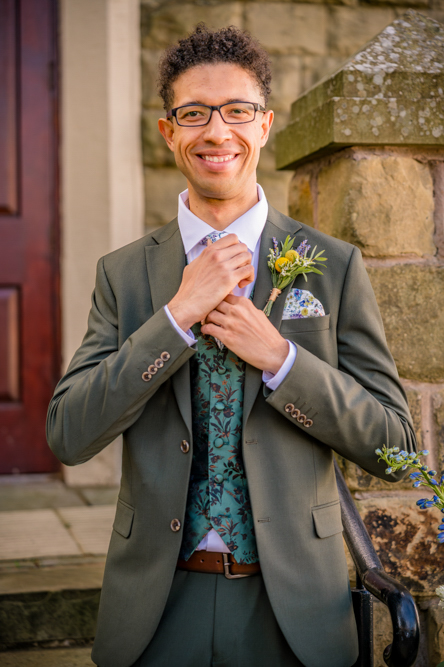 Close up detail of the groom tightening his tie on the wedding morning at Peel Street Baptist Church, Accrington