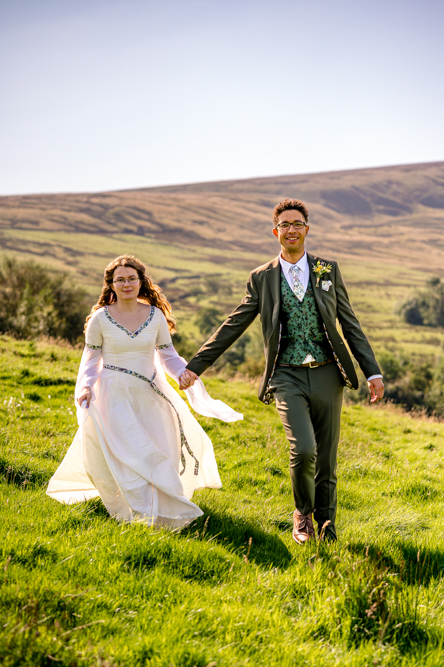 Bride and groom in the rolling hills at Cronkshaw Fold Farm, Rossendale, captured by Lancashire wedding photographer Rebekah Morecroft