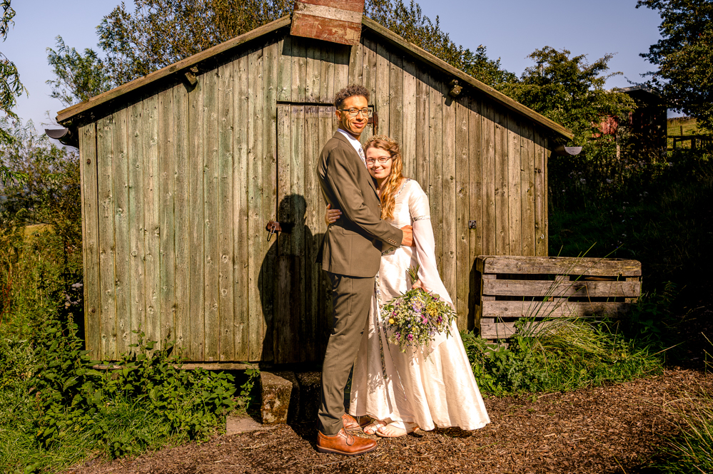 Bride and Groom holding each other infront of a wooden hut